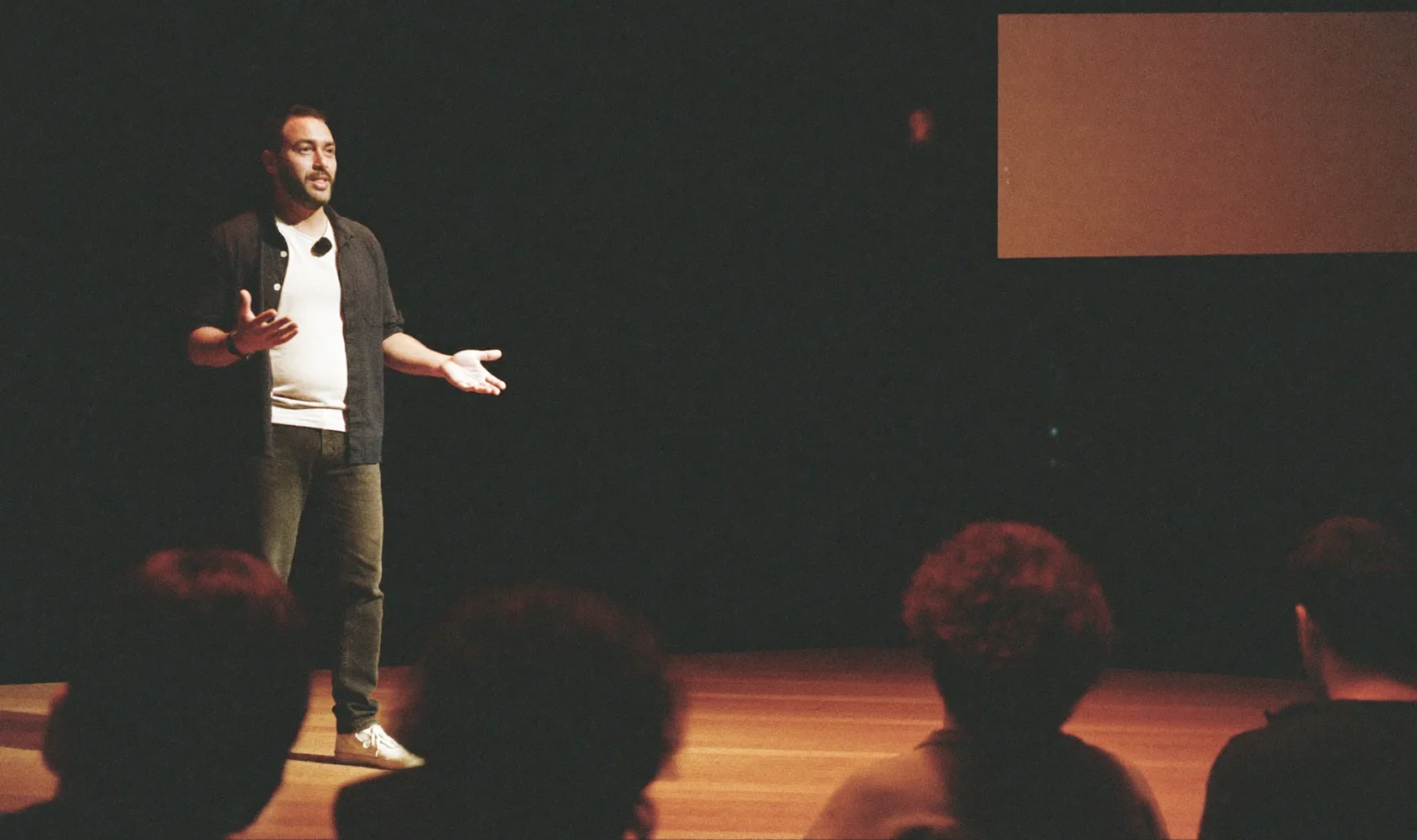 Business mentor speaking on stage to an audience at a small conference; illustrative scene